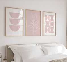 two framed art prints above a bed in a white and pink bedroom with neutral decor