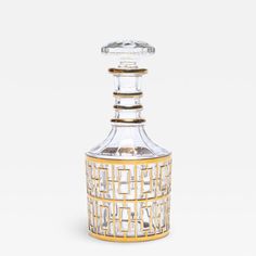 a clear and gold glass bottle with an intricate design on the top, in front of a white background