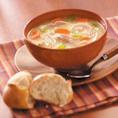 a wooden bowl filled with soup next to a piece of bread on top of a plate