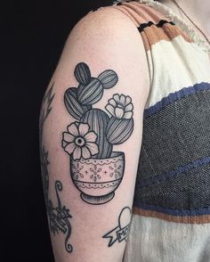 a woman with a tattoo on her arm has a potted cactus and flowers in it