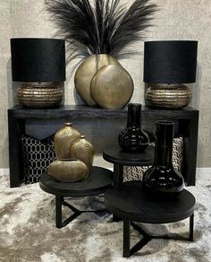 some black and gold vases are on a shelf next to two tables with lamps