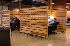 people working at desks made out of wooden pallets in an open office space