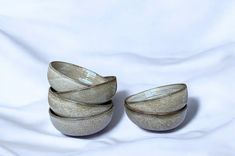 three silver bowls sitting on top of a white sheet