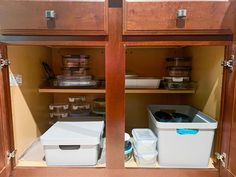 two white containers are sitting on the bottom shelf in this kitchen cabinet with wooden doors