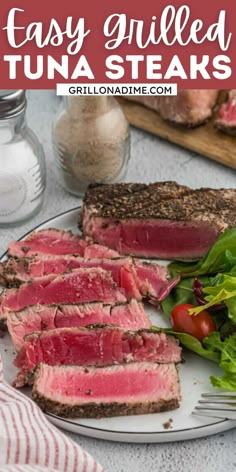 a plate with steak, lettuce and tomatoes on it next to some bread