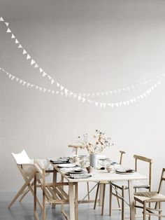 a dining room table with chairs and white buntings hanging from the ceiling over it