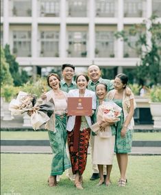 a group of people standing next to each other on top of a grass covered field