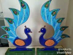 two blue peacock sculptures sitting on top of a green box in front of a white wall