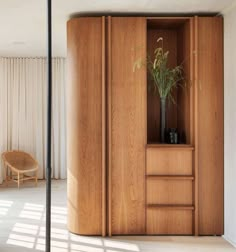 a room with wooden furniture and a plant in the corner on top of the cabinet