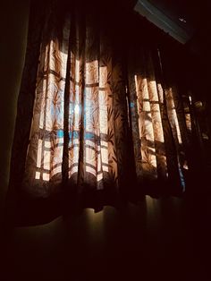 the sun is shining through the curtains in the dark room with light coming from behind