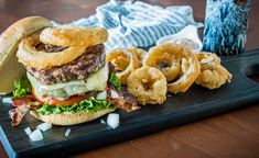 a plate with a hamburger and onion rings on it next to an owl figurine