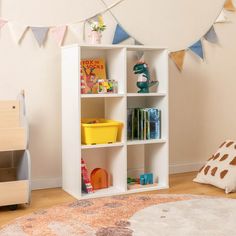 a child's room with toys and bookshelves on the floor in front of a wall decorated with bunting