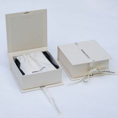 an open white box with a black tie in it next to a tag on the side