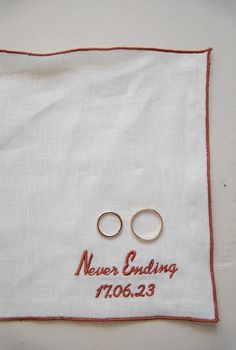 two gold wedding rings on top of a white cloth with the words never ending in red