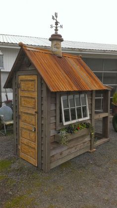 a small wooden shed with a metal roof and flower boxes on the window sill