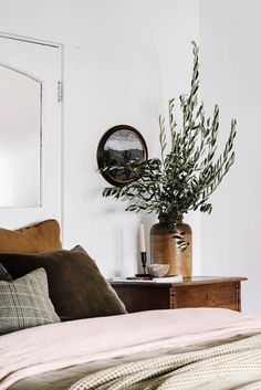 a bedroom with a bed, mirror and plant in the corner on top of it