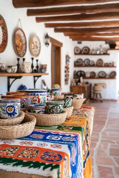 many bowls and baskets are sitting on the table in front of some wall hangings