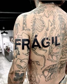 a man with tattoos on his back has the word fragil written in black ink