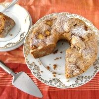 a plate with a cake on it next to a fork and two plates that have slices taken out of it