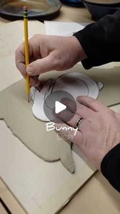 a person is working on a paper plate with a pencil in their left hand and another piece of cardboard behind them