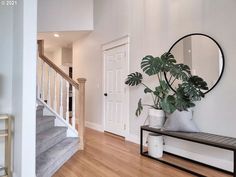 there is a plant on the table in front of the mirror and stairs to the second floor