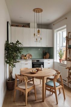 a table and chairs in a small kitchen with white cabinets, wood floors and wooden flooring