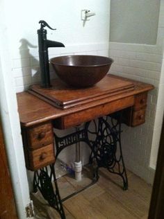 an old fashioned sewing table with a bowl on top and a faucet underneath