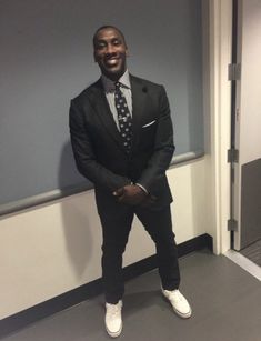 a man in a suit and tie standing next to a wall