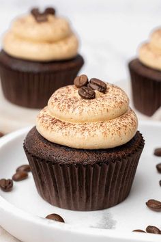 chocolate cupcakes topped with frosting and coffee beans on a white platter