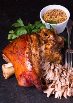 a large piece of meat sitting on top of a table next to a fork and bowl