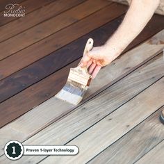 a person with a paintbrush painting a wooden deck