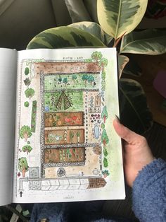 a person holding an open book in front of a planter filled with lots of plants