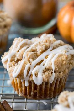 pumpkin muffins with white icing on a cooling rack next to cinnamon sticks