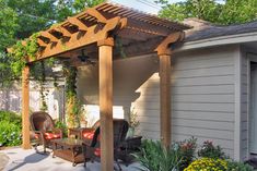 a covered patio with furniture and flowers in the foreground, next to a house