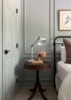 a bed room with a neatly made bed and a lamp on the end table next to it