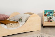 a wooden bed with pillows and blankets on it next to a book shelf filled with books