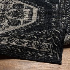 a black and white rug on top of a wooden floor