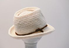 a white crocheted hat with brown ribbon around the brim on a mannequin head