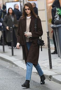 a woman is walking down the street with her hand in her pocket and looking at her cell phone