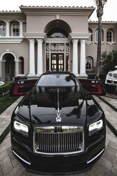 two rolls royces parked in front of a mansion