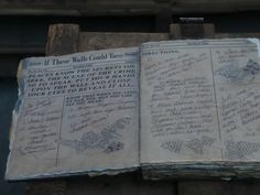 an old book with writing on it sitting on top of a piece of wood in front of a building