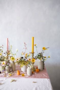 a table topped with vases filled with different types of flowers next to two candles