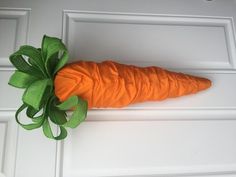 an orange carrot with a green bow on it's head hanging from a white door