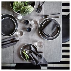 the table is set with black and white plates, napkins, and silverware