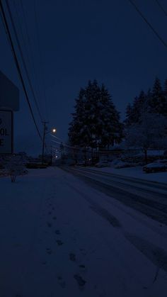 a snowy street at night with snow on the ground and power lines in the background