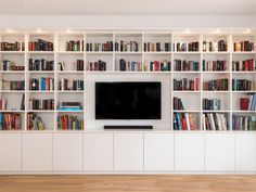 an entertainment center with bookshelves and a flat screen tv mounted on the wall