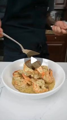 a white bowl filled with food on top of a table next to a knife and fork