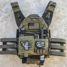 an army vest with patches and other items attached to the back, hanging on a wall