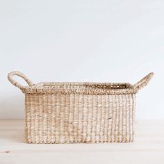 a wicker basket sitting on top of a wooden table next to a white wall