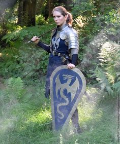 a woman dressed as a knight holding a shield